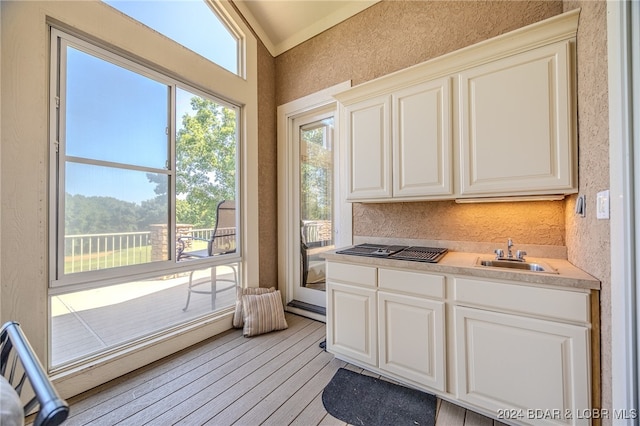 kitchen with light wood-type flooring, sink, and white cabinets