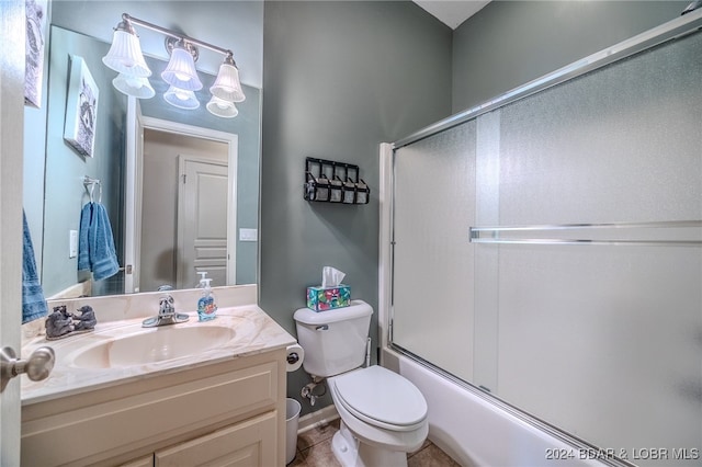 full bathroom with combined bath / shower with glass door, toilet, vanity, and tile patterned flooring