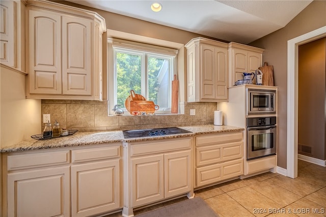 kitchen featuring decorative backsplash, appliances with stainless steel finishes, light stone counters, and light tile patterned floors