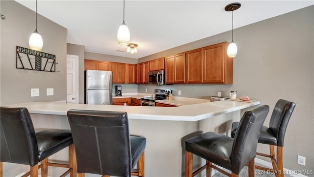 kitchen with pendant lighting, stainless steel appliances, a breakfast bar, and kitchen peninsula