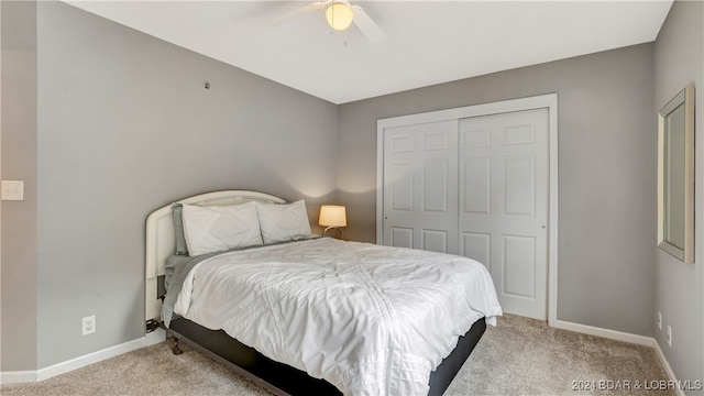 bedroom featuring light colored carpet, ceiling fan, and a closet