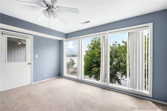 carpeted spare room featuring a textured ceiling and ceiling fan