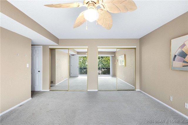 unfurnished bedroom featuring multiple closets, light colored carpet, and ceiling fan