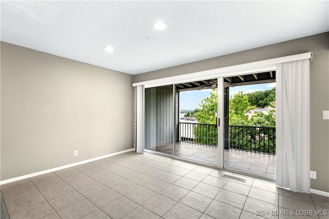 empty room with light tile patterned floors and a textured ceiling