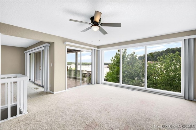 unfurnished room with light carpet, a textured ceiling, plenty of natural light, and ceiling fan