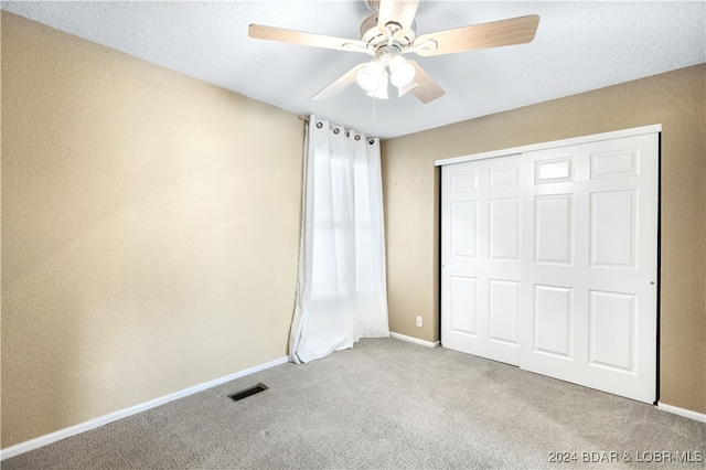 unfurnished bedroom with light colored carpet, a closet, and ceiling fan