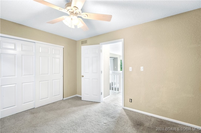 unfurnished bedroom featuring a closet, light colored carpet, and ceiling fan