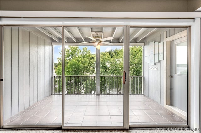 entryway featuring wooden walls and ceiling fan