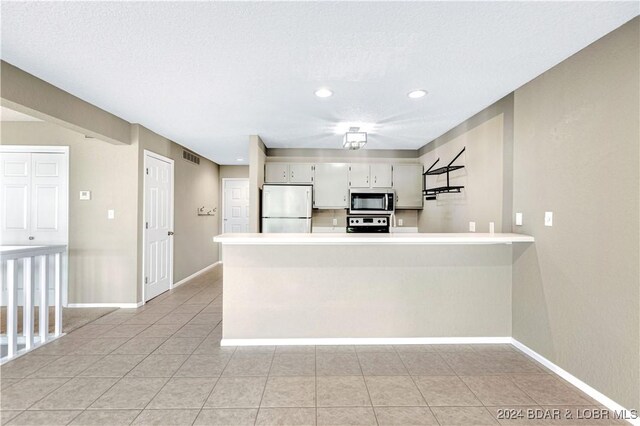 80 Regatta Bay Cir Unit 2B, Lake Ozark, MO 65049 - kitchen with freestanding refrigerator, stainless steel microwave, baseboards, a peninsula, and light countertops