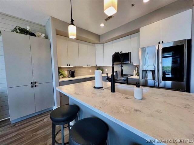 kitchen featuring backsplash, dark hardwood / wood-style floors, stainless steel fridge with ice dispenser, pendant lighting, and white cabinets