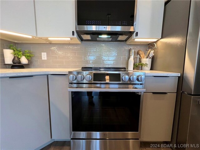 kitchen with appliances with stainless steel finishes, decorative backsplash, and white cabinets