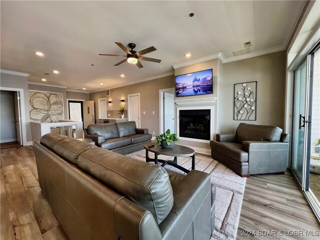 living room featuring ceiling fan, light wood-type flooring, and crown molding