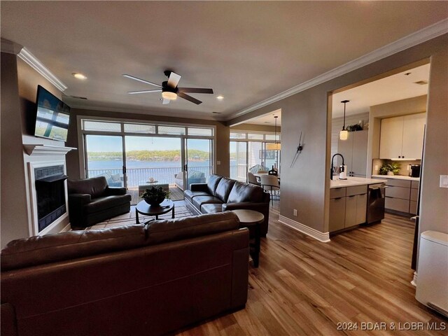 living room with light wood-type flooring, sink, ornamental molding, and ceiling fan