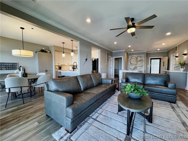 living room featuring ceiling fan, light hardwood / wood-style flooring, and ornamental molding