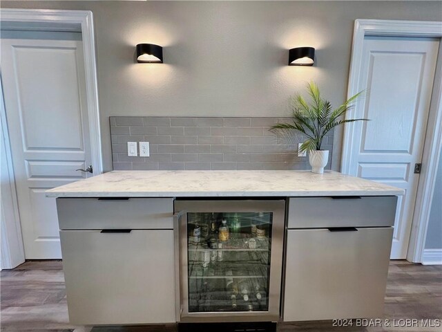 bar featuring backsplash, hardwood / wood-style flooring, and beverage cooler