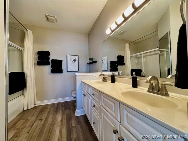 full bathroom featuring hardwood / wood-style floors, toilet, shower / bath combination with glass door, and dual vanity