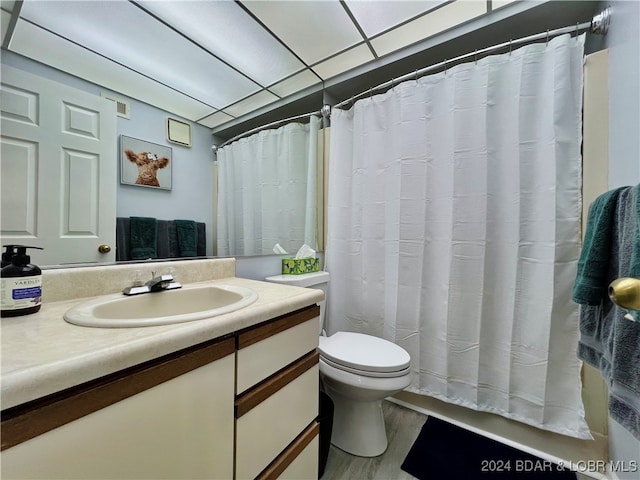 bathroom featuring vanity, toilet, hardwood / wood-style floors, and a drop ceiling