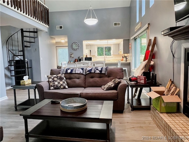 living room with a towering ceiling and light hardwood / wood-style flooring