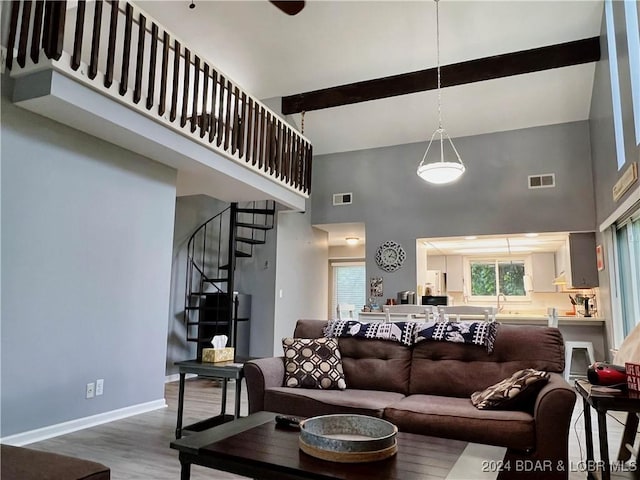 living room featuring wood-type flooring, beamed ceiling, and a high ceiling