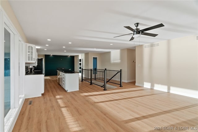 kitchen with light hardwood / wood-style floors, white cabinets, ceiling fan, and a kitchen island