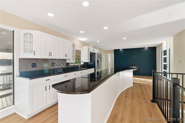 kitchen with black electric stovetop, stainless steel fridge with ice dispenser, light wood-type flooring, and white cabinets