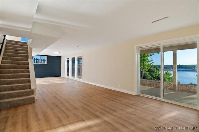 unfurnished living room with hardwood / wood-style flooring and a water view