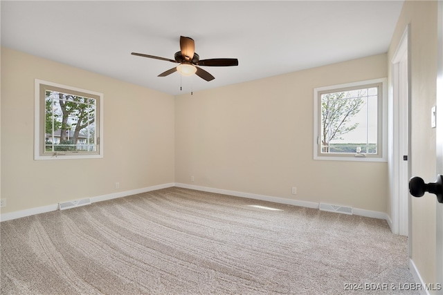 carpeted empty room featuring a wealth of natural light and ceiling fan