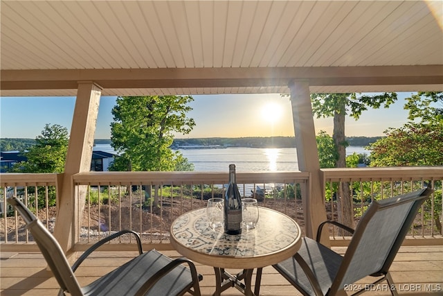 deck at dusk featuring a water view