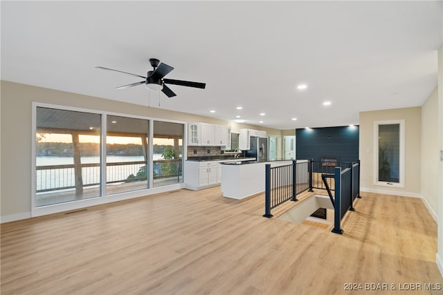 kitchen featuring a kitchen island, white cabinetry, a water view, a breakfast bar, and stainless steel refrigerator with ice dispenser