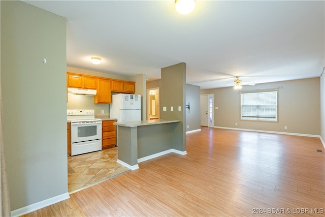 kitchen featuring kitchen peninsula, light hardwood / wood-style floors, white appliances, ceiling fan, and a kitchen breakfast bar