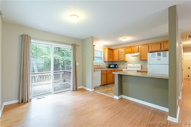 kitchen with sink, kitchen peninsula, white appliances, and light hardwood / wood-style floors