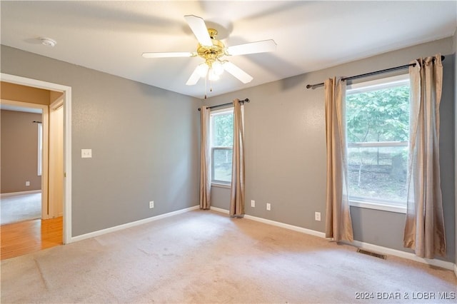 unfurnished room with light carpet, a wealth of natural light, and ceiling fan