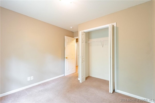 unfurnished bedroom with light carpet and a closet