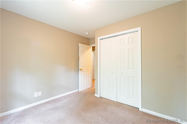 unfurnished bedroom with light carpet and a closet