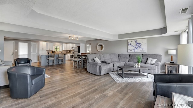 living room with light wood-type flooring and a tray ceiling