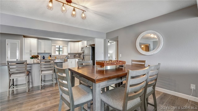 dining space featuring hardwood / wood-style flooring, a textured ceiling, and track lighting