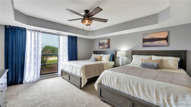 carpeted bedroom featuring ceiling fan, a raised ceiling, and a textured ceiling