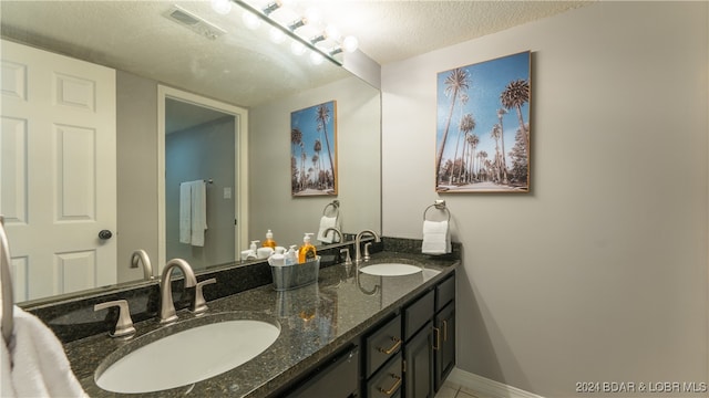 bathroom featuring double sink vanity and a textured ceiling