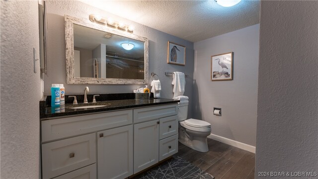 bathroom with hardwood / wood-style floors, toilet, a textured ceiling, and vanity