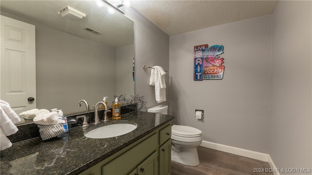 bathroom with a textured ceiling, toilet, vanity, and hardwood / wood-style flooring