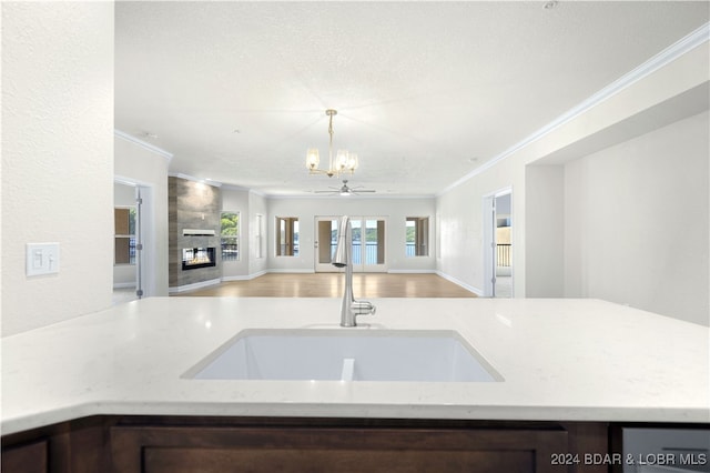 kitchen featuring sink, ornamental molding, light stone counters, a chandelier, and a textured ceiling