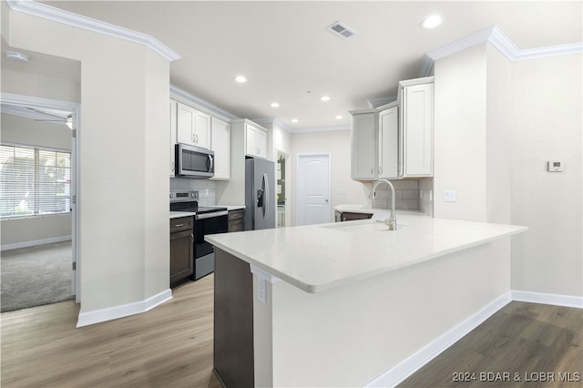 kitchen with kitchen peninsula, stainless steel appliances, light colored carpet, and tasteful backsplash