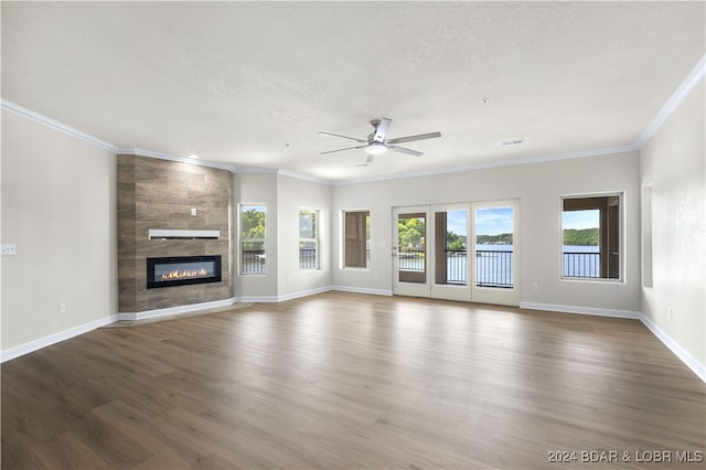 unfurnished living room featuring ceiling fan, wood-type flooring, a tile fireplace, and a textured ceiling