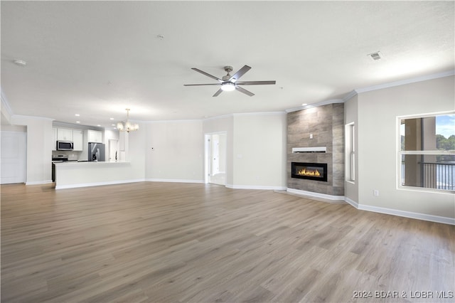 unfurnished living room with ceiling fan with notable chandelier, crown molding, light hardwood / wood-style flooring, and a fireplace