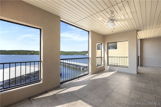 unfurnished sunroom featuring ceiling fan and a water view