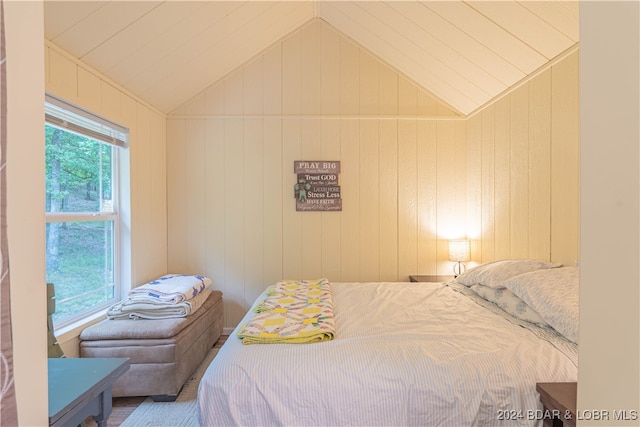 bedroom with wood walls and lofted ceiling