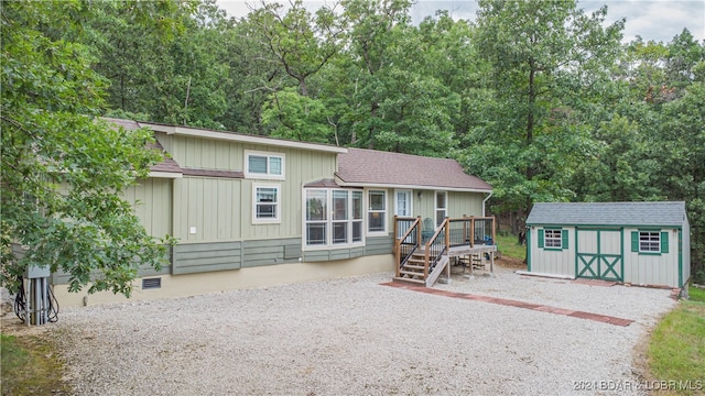 rear view of property featuring a storage unit