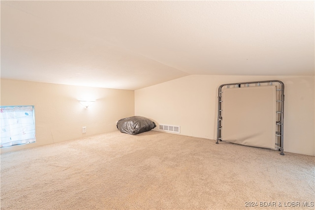 bonus room with lofted ceiling and light colored carpet