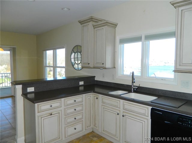 kitchen with a peninsula, a sink, plenty of natural light, dishwasher, and dark countertops