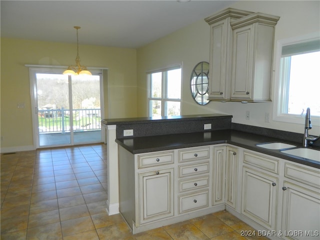 kitchen with light tile patterned floors, sink, kitchen peninsula, and a chandelier